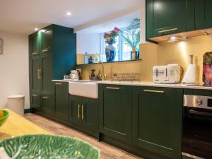 a green kitchen with green cabinets and a sink at Southbank in Bath