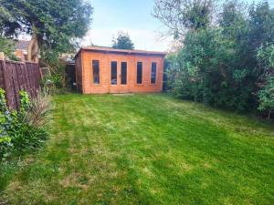 a small wooden cabin in a yard with a lawn at Gilpin villa 4Bedroom WiFi, Parking, Netflix, Garden in Gloucester