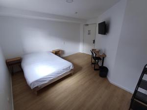 Cette petite chambre comprend un lit blanc et une télévision. dans l'établissement CRYSTAL HOTEL, à Claye-Souilly