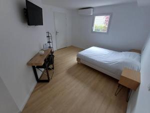 Dormitorio con cama, escritorio y TV en CRYSTAL HOTEL, en Claye-Souilly