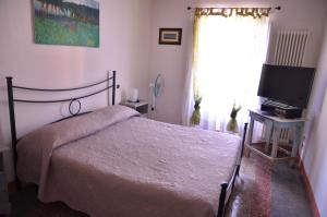 um quarto com uma cama, uma televisão e uma janela em Rifugio al mare della Versilia em Strettoia