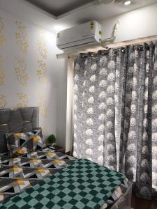 een slaapkamer met een geruit gordijn en een bed bij Vision Studio Apartment in Ghaziabad