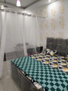 een slaapkamer met een bed met een geruit bij Vision Studio Apartment in Ghaziabad