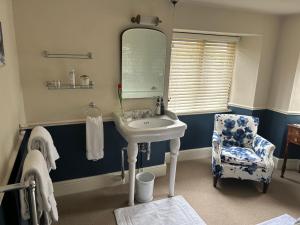 baño con lavabo, espejo y silla en The Old Rectory Somerset, en North Perrott