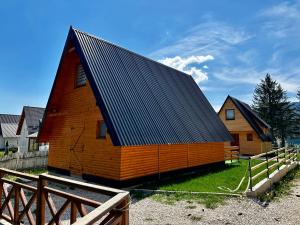 eine große Holzscheune mit schwarzem Dach in der Unterkunft KRAJINA III in Vlasic