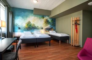 クリスティアンスンにあるThon PartnerHotel Storgataのベッド2台が備わる客室で、壁には絵画が飾られています。