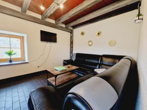 ein Wohnzimmer mit einem Ledersofa und einem Tisch in der Unterkunft Le Petit Hangy in Fresse-sur-Moselle