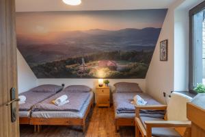 two beds in a room with a painting on the wall at Koliba Pod Horů in Dolní Bečva