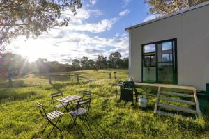 a group of chairs and a table in a field at Sithuri Tiny House in Windeyer