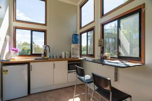 una cocina con 2 sillas y una barra con ventanas en Sithuri Tiny House en Windeyer