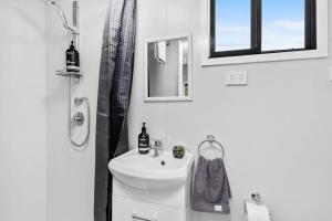 a white bathroom with a sink and a mirror at Azaltie in Kangaroo Valley