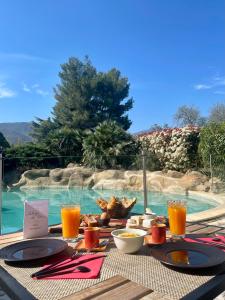 una mesa con comida y bebida junto a una piscina en Auberge Du Roua, en Argelès-sur-Mer