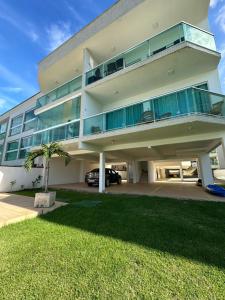 a large white building with a balcony and a palm tree at Praia Grande, Angra dos Reis in Angra dos Reis