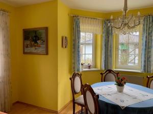 comedor con mesa, sillas y paredes amarillas en Ferienhaus Loretto, en Wölzing