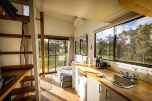 a kitchen with a sink and two large windows at Tiny House Farmstay at Dreams Alpaca Farm - A Windeyer Outback Experience in Windeyer