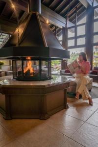 a woman reading a book in front of a fireplace at Pousada Vovó Carolina in Gramado