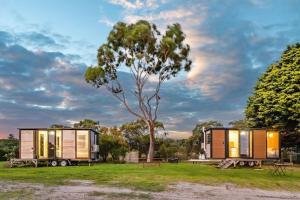 two tiny houses parked in a field with a tree at Tiny House Big View in Boneo