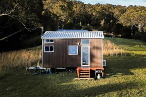 a brown tiny house sitting in a field at Little Magic on Magic Mountain in Coolangatta