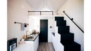 eine kleine Küche mit einer schwarzen Treppe in einem winzigen Haus in der Unterkunft The Perch in Korweinguboora