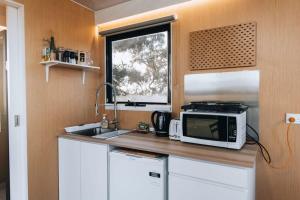 uma cozinha com um micro-ondas, um lavatório e uma janela em Bush Retreat em Alberton West