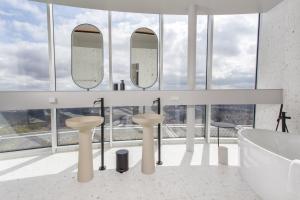 a bathroom with two sinks and a tub and mirrors at Vilnius TV Tower Apartments DEBESYS in Vilnius
