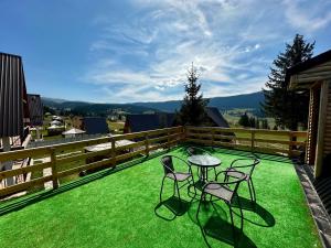 a patio with two chairs and a table on the grass at Krajina IV & jacuzzi in Vlasic
