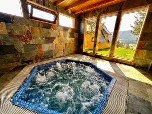 a hot tub in the middle of a room with windows at Krajina IV & jacuzzi in Vlasic