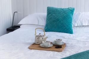 a tray with two cups and a tea set on a bed at Womburra Vineyard Tiny Stay 