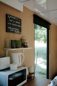eine Küche mit einer Mikrowelle und ein Fenster mit Aussicht in der Unterkunft Cockatoo Cabin in Palmwoods