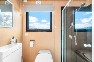 a bathroom with a shower and a toilet and a window at Cabernet Tiny House in Windeyer