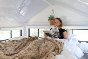 a woman laying in bed reading a book at Wombat Cottage in Crackenback
