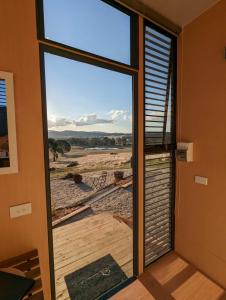 a door to a balcony with a view of a field at Farm Stay at Sheltered Paddock 