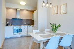 a kitchen with a white table and white chairs at Aquarius Kołobrzeg in Kołobrzeg +32 photos