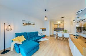 a living room with a blue couch and a kitchen at Aquarius Kołobrzeg in Kołobrzeg