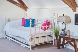 una camera da letto con un letto bianco con cuscini rosa e blu di Hidden Hayloft a Holmesfield