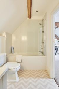 a white bathroom with a toilet and a bath tub at Hidden Hayloft in Holmesfield