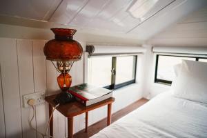 a bedroom with a bed and a table with a lamp at Tiny Regen Farm Stay in Lawrence
