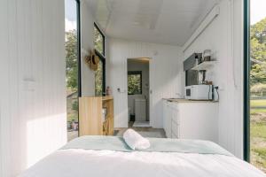 a bedroom with a white bed and a kitchen at Rainforest Sunsets in Kuranda
