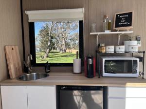 a kitchen with a counter with a microwave and a window at Tiny Towrang 