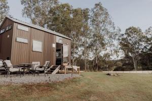 Hill Creek Tiny House في Perwillowen: منزل بطاولة وكراسي في ميدان