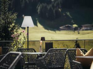 uma mesa com cadeiras e um candeeiro numa varanda em Hotel Bergkristall Zillertal em Hippach