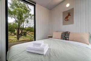 um quarto com uma cama grande e uma janela grande em The Meadows Tiny House em Macclesfield