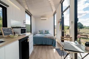 a tiny house with a bed and a kitchen with windows at JBJK Homestead in Yarck
