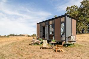 a black tiny house with a table and chairs at Tiny Divine Farmstay in Korweinguboora