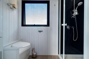 La salle de bains est pourvue d'une douche, de toilettes et d'une fenêtre. dans l'établissement JBJK Homestead, à Yarck