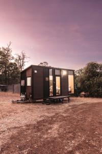 a black tiny house sitting in a field at Wally's Retreat 1 in Balingup