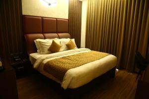 1 dormitorio con 1 cama grande y cabecero marrón en SAJ Earth Resort & Convention Center , Kochi, en Nedumbassery