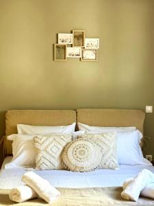 ein Bett mit weißen Kissen und Bildern an der Wand in der Unterkunft Villa Korina in Posidhonía