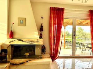 a living room with a fireplace and a patio at Villa Korina in Posidhonía