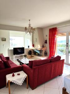ein Wohnzimmer mit zwei roten Sofas und einem TV in der Unterkunft Villa Korina in Posidhonía